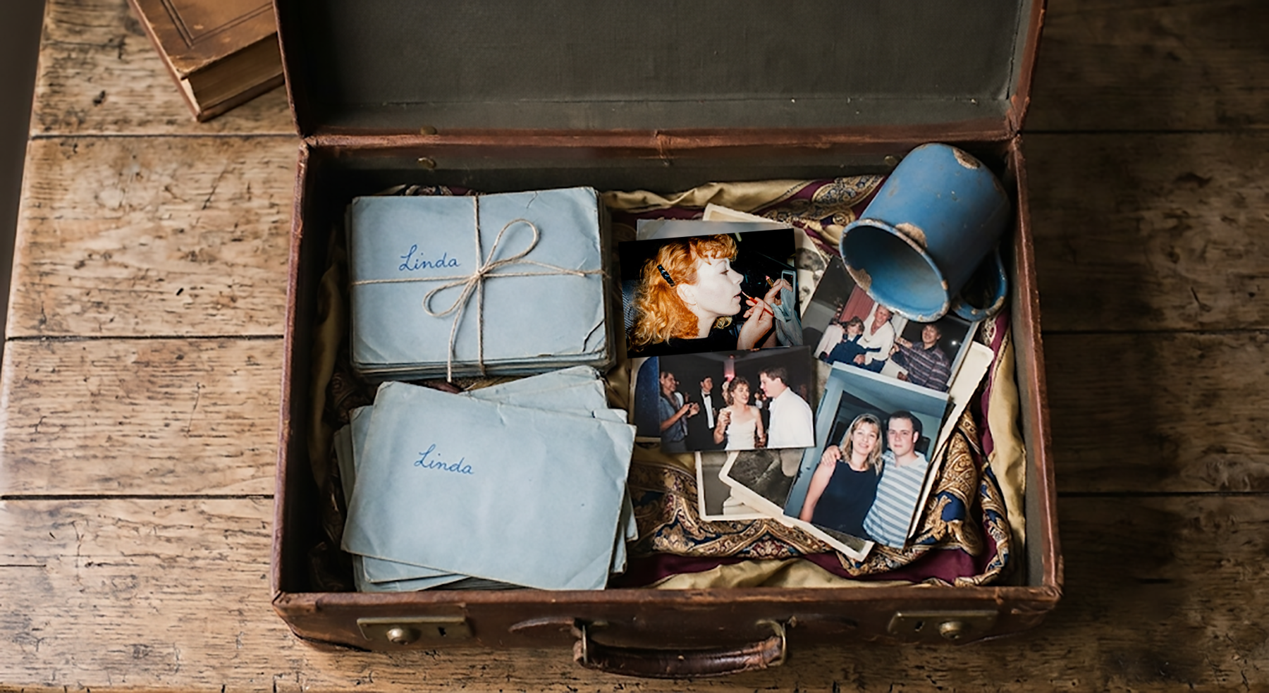 An open suitcase containing bundles of old letters tied with string, and a scattering of black and white photographs.